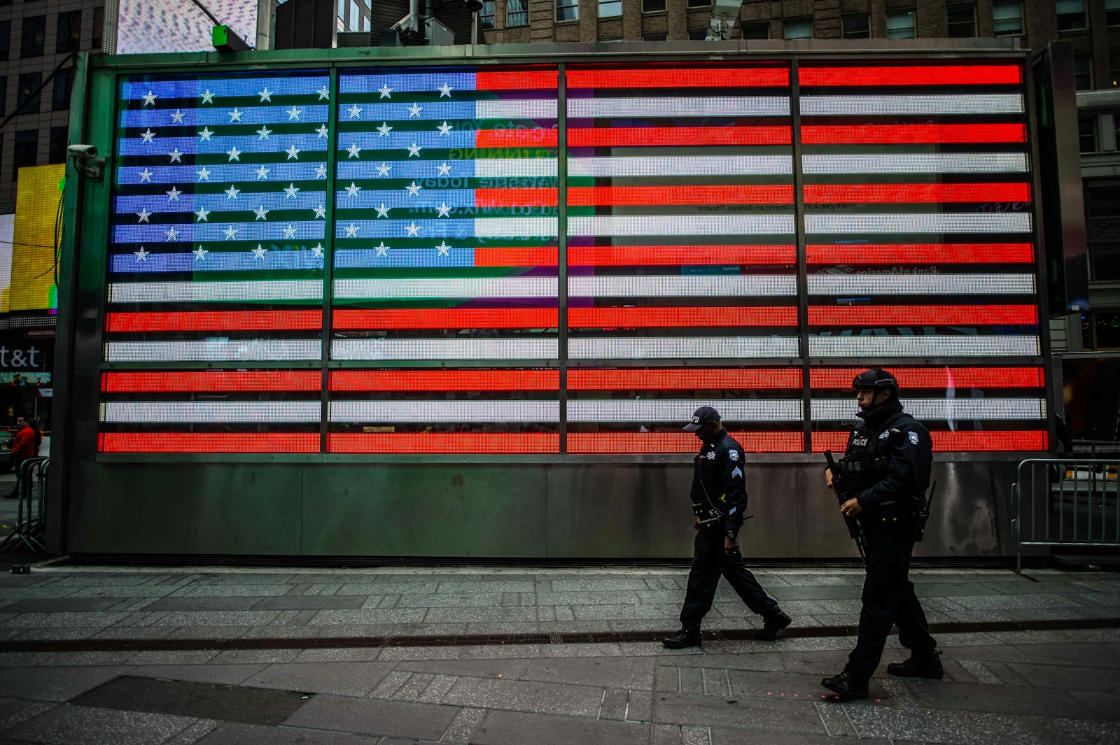 two man walks near USA flag wall